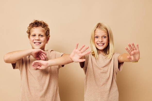 Portrait d'enfants mignons en t-shirts beiges posant pour s'amuser fond isolé