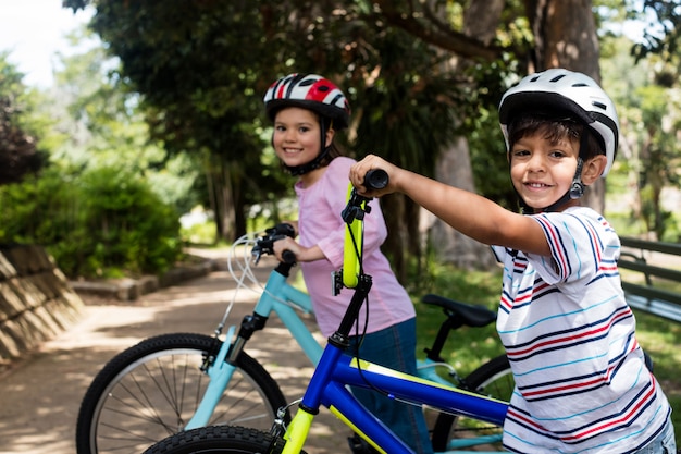 Portrait d'enfants souriants debout avec vélo dans le parc