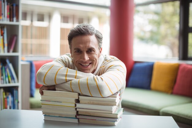 Portrait d'enseignant heureux s'appuyant sur un livre dans la bibliothèque