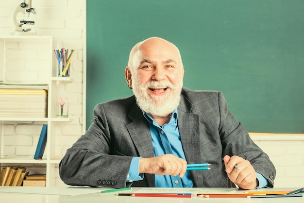 Portrait d'un enseignant senior assis au bureau dans la classe enseignant meilleur ami des apprenants enseignant à l'école