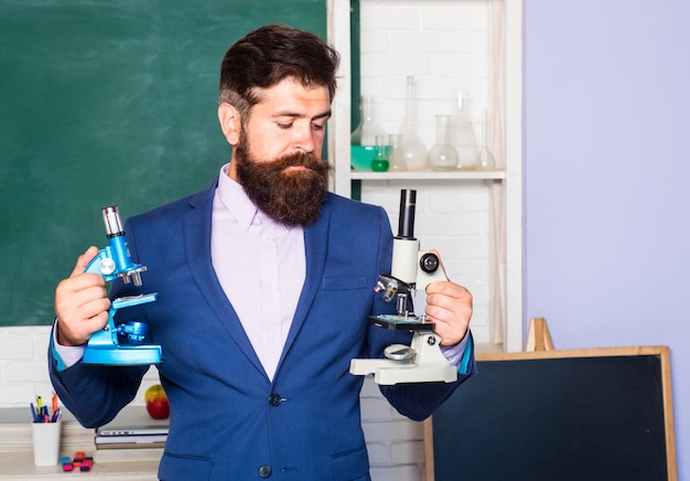 Portrait d'un enseignant de sexe masculin pensant avec un mentor de professeur de microscope dans une salle de classe