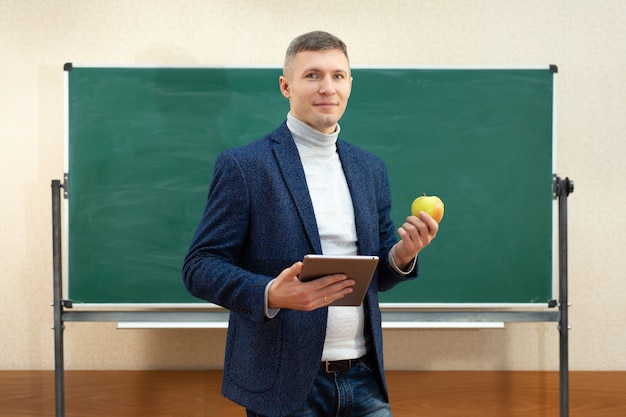 Portrait d'un enseignant souriant avec une tablette et une pomme verte