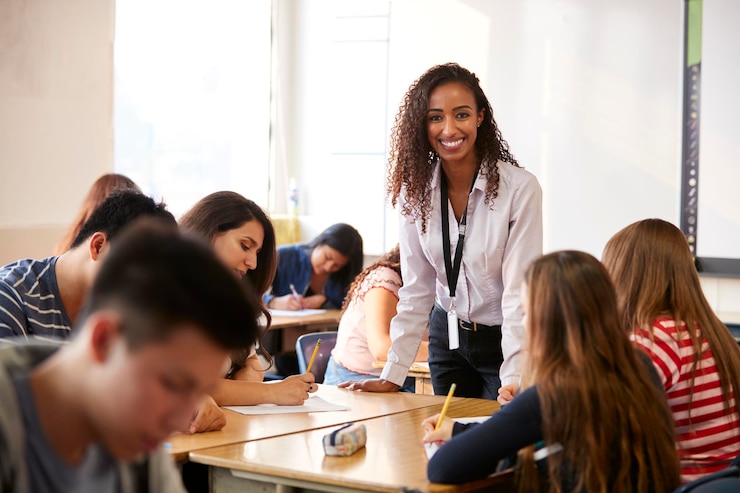 Photo portrait d'une enseignante de lycée souriante debout à la table des élèves.