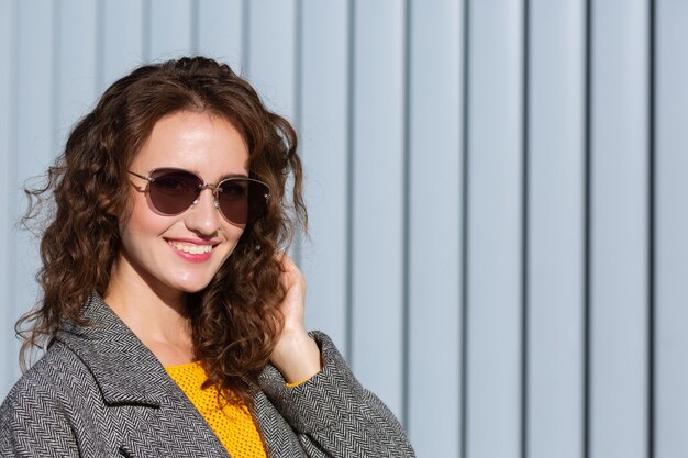 Portrait ensoleillé d'une joyeuse fille hipster marchant dans la rue, vêtue d'une tenue tendance. Espace pour le texte