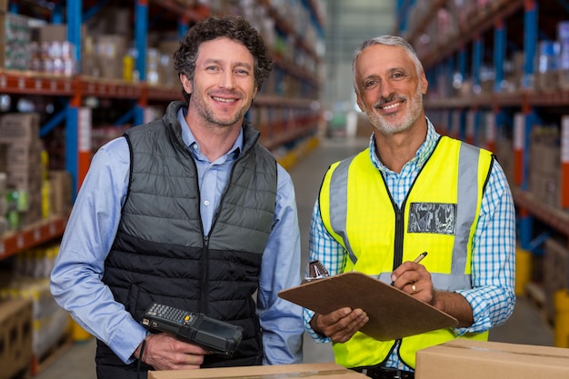 Portrait, entrepôt, ouvriers, debout, presse-papiers, barcode, scanner