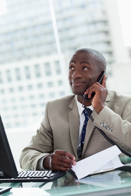 Portrait d&#39;un entrepreneur heureux qui fait un appel téléphonique en lisant un document