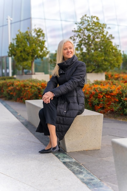 Portrait d'entreprise d'une femme d'affaires d'âge moyen assise à l'extérieur d'un gratte-ciel de bureau