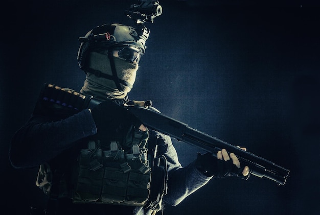 Portrait d'épaule des troupes d'élite de l'armée soldat équipe tactique antiterroriste avec casque de fusil de chasse avec imageur thermique cachant le visage derrière un fusil armé de masque avec tir de studio à portée optique sur noir