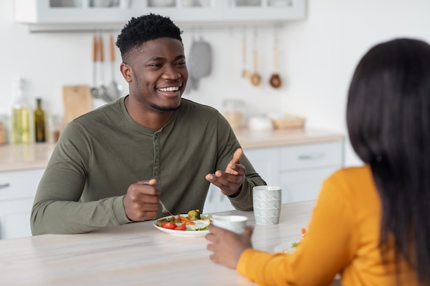 Portrait d'époux afro-américains heureux bavardant pendant le petit-déjeuner dans la cuisine