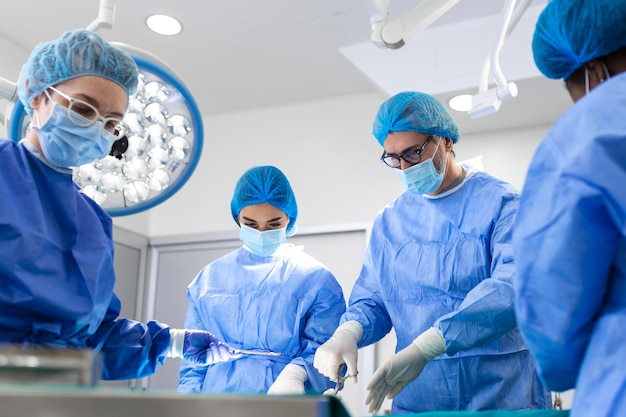 Portrait d'une équipe de chirurgiens multiethniques au travail dans une salle d'opération Plusieurs médecins entourant un patient sur une table d'opération pendant leur travail Chirurgiens d'équipe au travail dans une salle d'opération