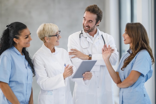 Portrait d'une équipe diversifiée de médecins et d'infirmières se tenant ensemble et utilisant une tablette numérique dans un hôpital.