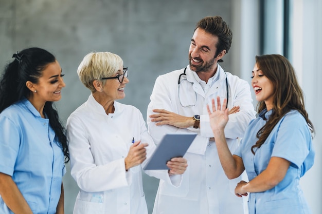 Portrait d'une équipe médicale confiante de médecins et d'infirmières debout avec les bras croisés dans un couloir d'hôpital et regarde la caméra.