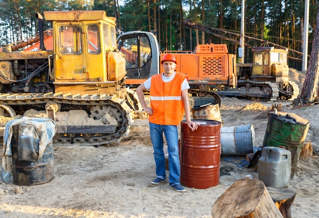 Portrait de l'équipement de construction du conducteur assis près des fûts de carburant