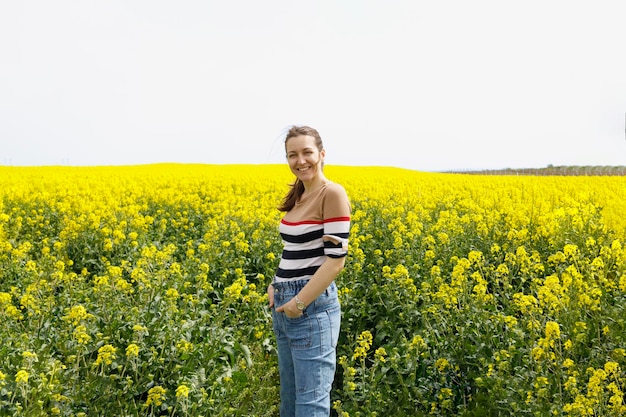 Portrait d'été d'une femme heureuse debout dans un champ jaune