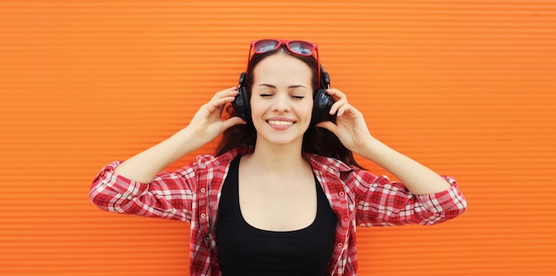 Portrait d'été d'une jeune femme heureuse et souriante écoutant de la musique dans des écouteurs