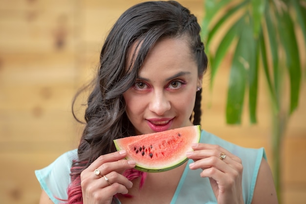 Portrait d'été de jeune femme mexicaine mangeant une tranche de pastèque