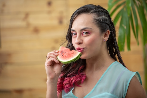 Portrait d'été de jeune femme mexicaine mangeant une tranche de pastèque