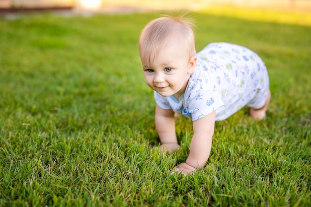 Portrait d'été de joyeux bébé drôle à l'extérieur sur l'herbe dans le champ. Enfant apprenant à ramper