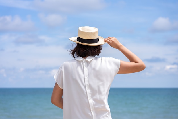 Portrait d&#39;été en plein air de jeune femme asiatique portant un chapeau élégant et des vêtements se tenant debout sur la plage