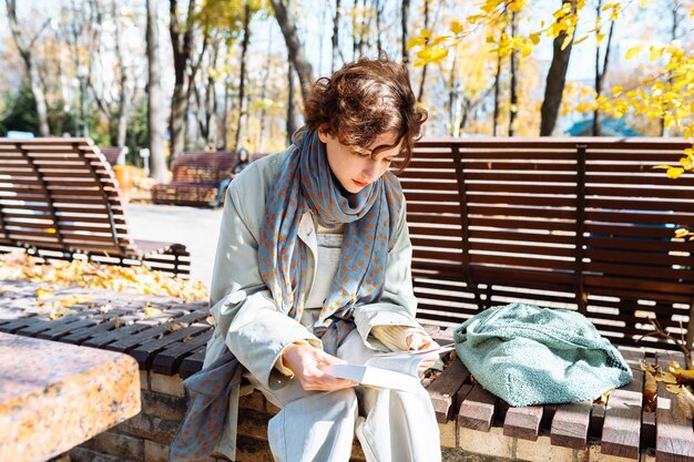 Portrait d'un étudiant adolescent avec un bloc-notes dans les mains dans un parc en automne