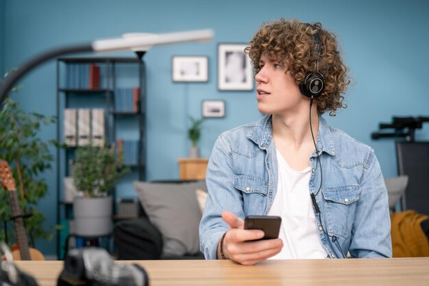 Portrait d'étudiant adolescent écoutant de la musique assis au bureau dans son salon à la maison