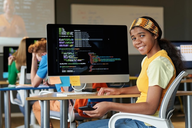 Portrait d'un étudiant afro-américain souriant à la caméra tout en apprenant l'informatique en classe