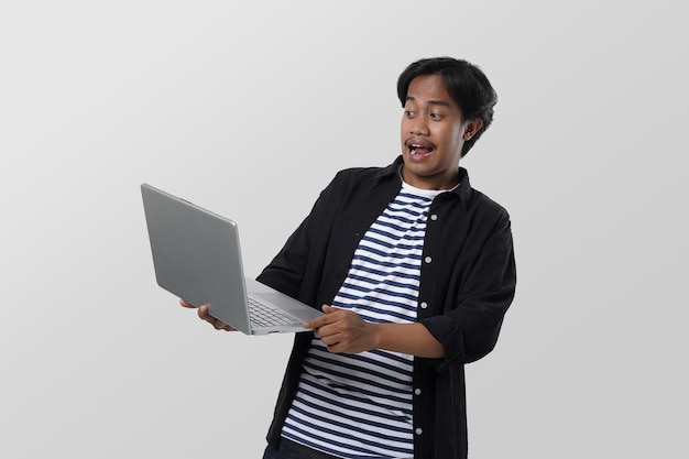 portrait d'un étudiant asiatique intelligent tenant un ordinateur portable dans une main avec un geste de la main et ayant l'air sérieux