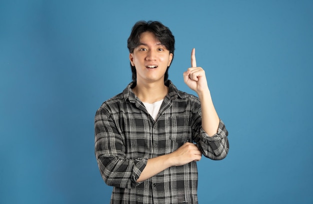 Portrait d'un étudiant asiatique posant sur un fond bleu