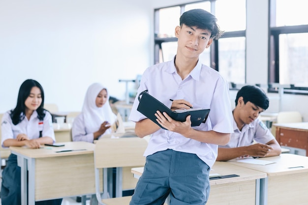 Portrait d'un étudiant asiatique souriant portant un uniforme scolaire, debout en toute confiance en classe