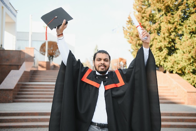 Portrait d'étudiant indien réussi en robe de graduation pouce vers le haut