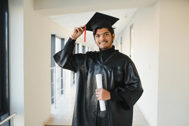 Portrait d'étudiant indien réussi en robe de graduation.