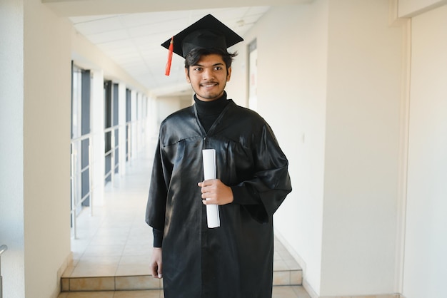 Portrait d'étudiant indien réussi en robe de graduation.