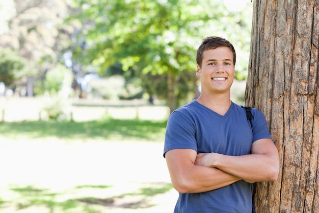 Portrait d&#39;un étudiant musclé appuyé contre un arbre