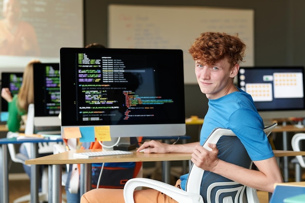 Portrait d'un étudiant regardant la caméra tout en utilisant l'ordinateur lors d'un cours informatique