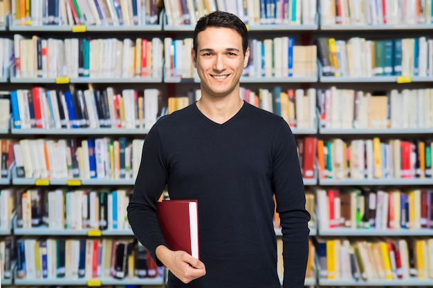 Portrait d&#39;un étudiant souriant heureux dans une bibliothèque