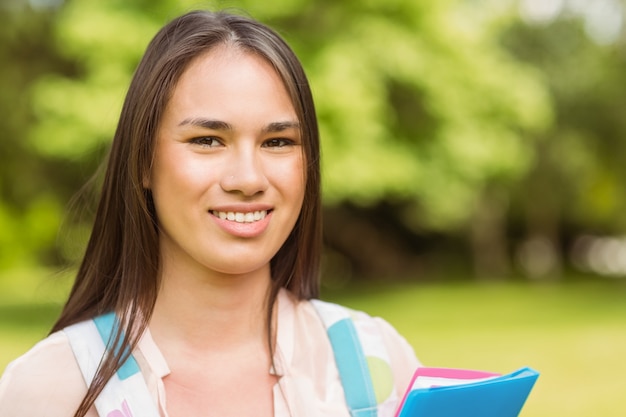 Portrait d&#39;un étudiant souriant avec un sac à bandoulière et un livre de tenue