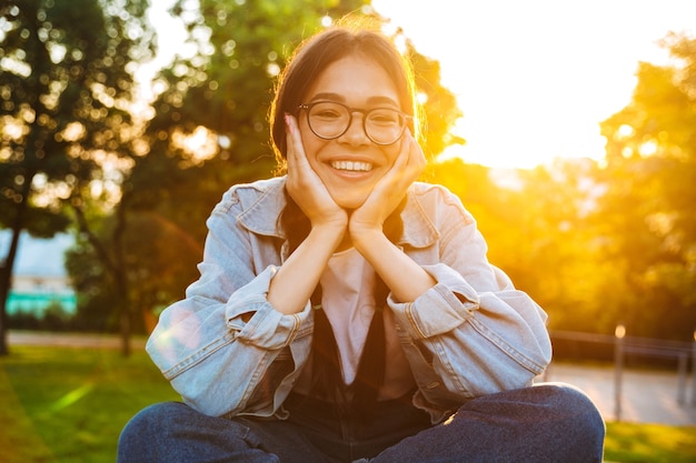 Portrait d'une étudiante adolescente joyeuse et joyeuse assise à l'extérieur dans un magnifique parc verdoyant