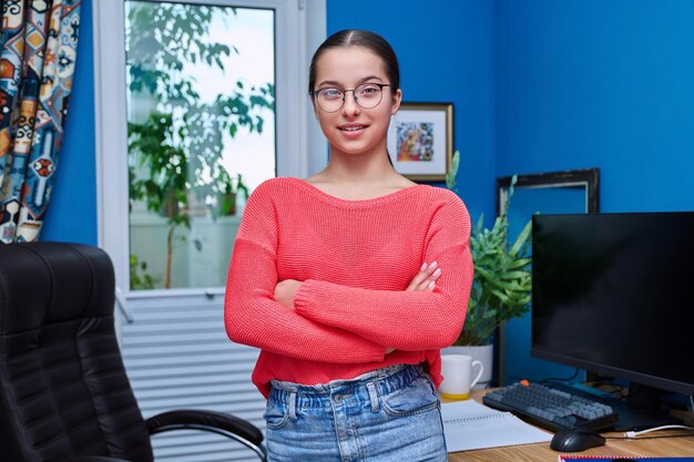 Portrait d'une étudiante adolescente à la maison près d'un bureau avec ordinateur