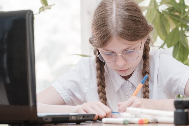 Portrait d'une étudiante appréciant l'apprentissage dans un bureau de coworking à l'aide d'un ordinateur portable pour la recherche, pigiste lors de la création d'un projet de prise de notes à distance. Notes de dessin concentrées de l'élève