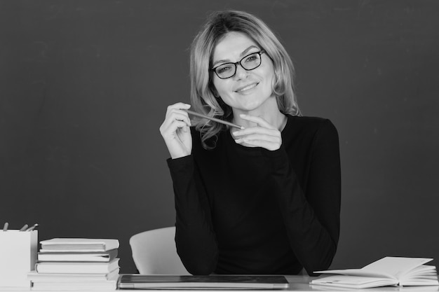 Portrait d'une étudiante ou d'une enseignante blonde séduisante souriante sur un tableau noir vert dans une salle de classe au collage ou au lycée