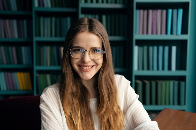 Portrait d'une étudiante gestionnaire avec des lunettes dans la bibliothèque