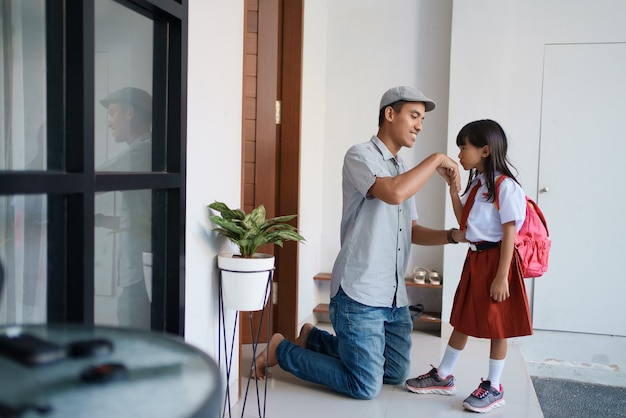 Portrait d'une étudiante indonésienne de l'école primaire secoue et embrasse la main de son père avant d'aller à l'école