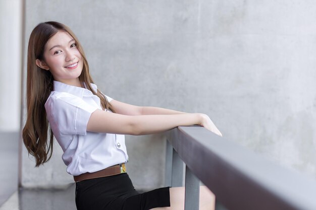 Portrait d'une étudiante thaïlandaise en uniforme d'étudiant universitaire Asiatique belle fille assise souriante