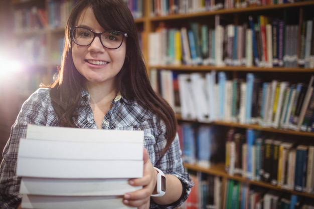 Portrait d'étudiantes tenant une pile de livres dans la bibliothèque