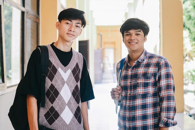 Portrait d'étudiants adolescents souriants debout ensemble sur le campus d'un lycée