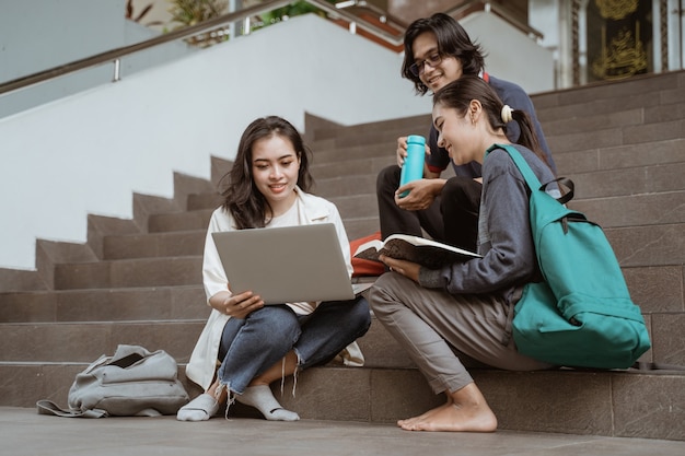 Portrait d'étudiants s'asseoir à travailler en groupes sur le campus escaliers étage