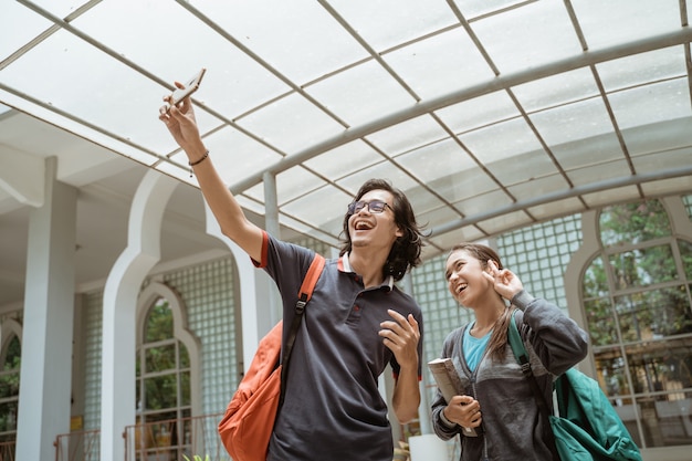 Portrait d'étudiants très heureux et souriant prendre un selfie sur la cour avant du campus