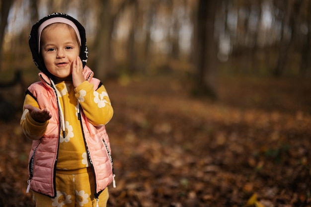 Portrait extérieur d'automne de belle petite fille heureuse dans la forêt