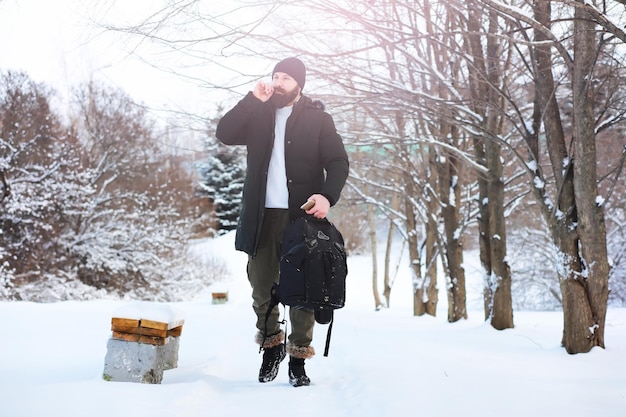 Portrait extérieur d'un bel homme en manteau et croûte. Homme barbu dans les bois d'hiver.