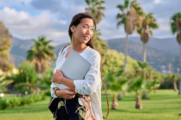 Portrait extérieur d'une jeune femme avec un ordinateur portable et un sac à dos